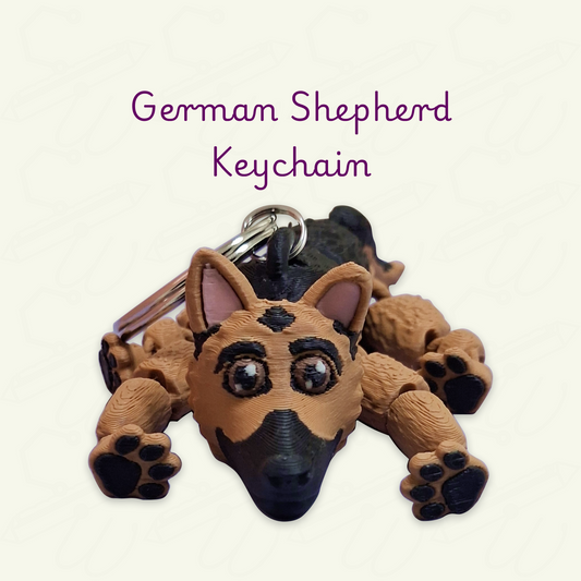 A 3D-printed German Shepherd keychain shaped like the dog lying down, with a metal keyring attached. The keychain is brown with black markings and small pink inner ears.
