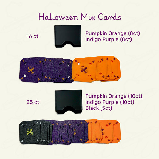 Halloween mix cards sets spread out on a tan background. 16 count contains 8 Pumpkin Orange cards and 8 Indigo Purple cards with a slim black case. 25 count contains 10 Pumkin Orange cards, 10 Indigo Purple cards, and 5 Black cards wih a slim black case.