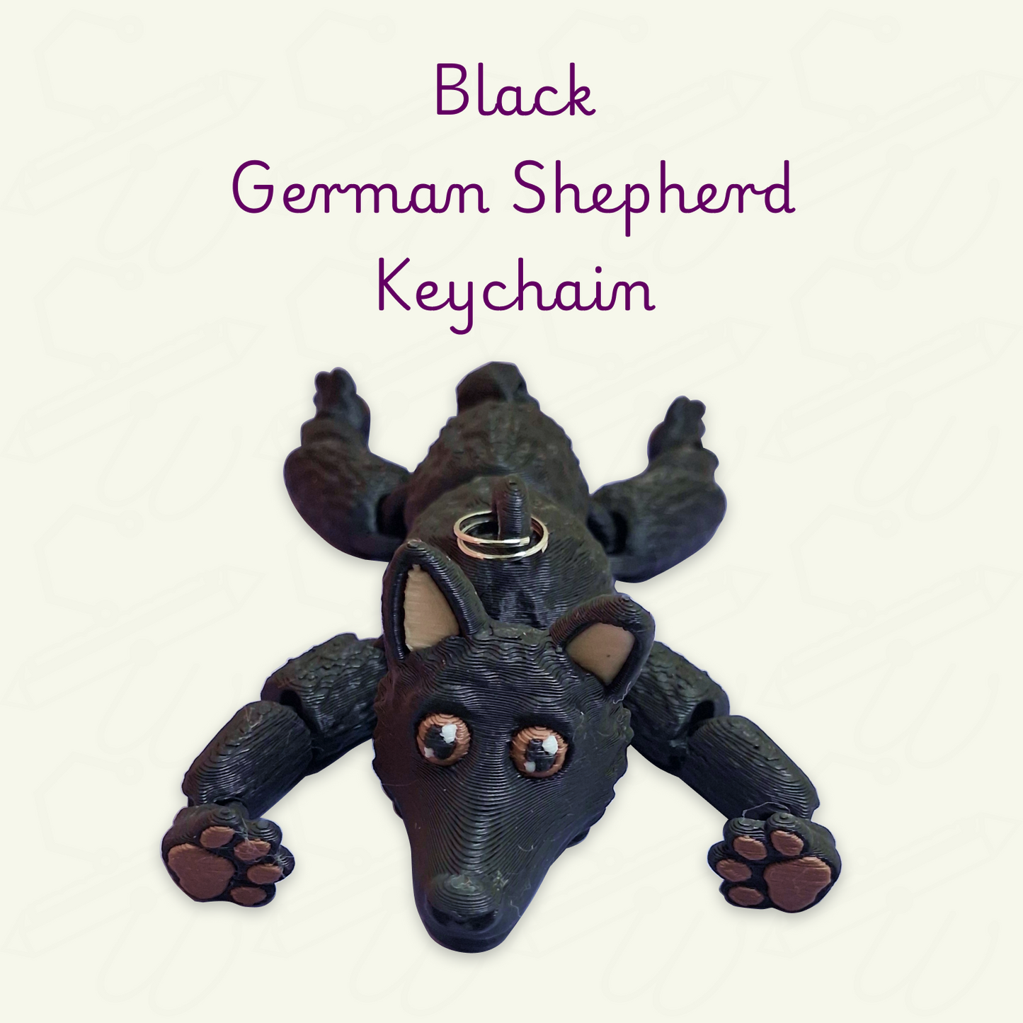 A black German Shepherd keychain shaped like a dog lying down on a light cream background. The keychain has beige inner ears and brown paw pads.